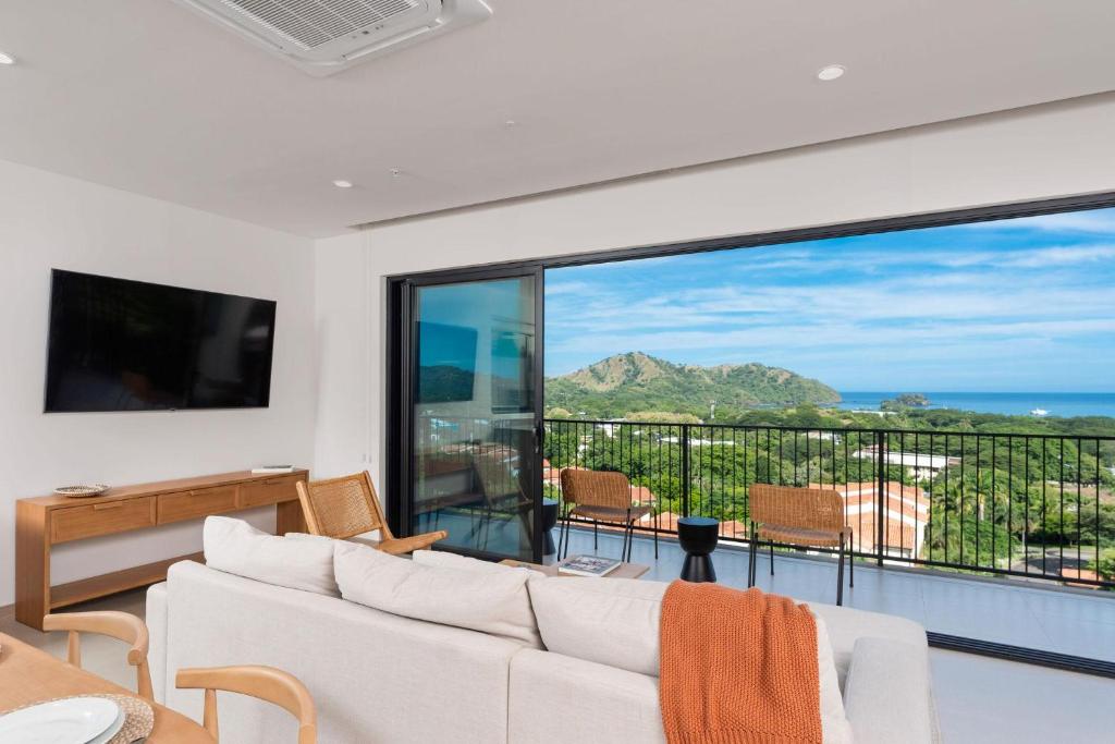 a living room with a white couch and a large window at Sol Pacífico at Naumi, Ocean Views & Beach Club in Sardinal