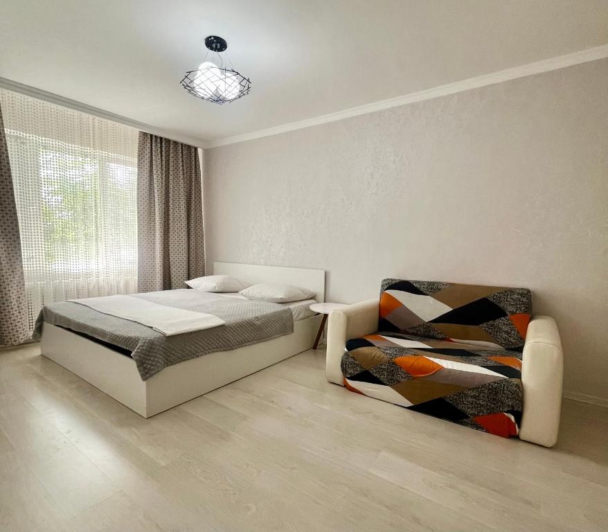 a bedroom with a bed and a chair at Уютная квартира в 4 мкр Авангарда in Atyraū