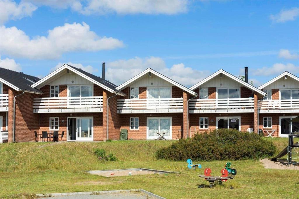 Un gran edificio de apartamentos de ladrillo con balcones y un parque infantil. en 0291-Romo-Vestergade-3-Ap-65, en Havneby