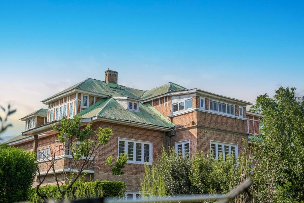 une grande maison en briques avec un toit vert dans l'établissement SaffronStays Awakening Suite, à Srinagar