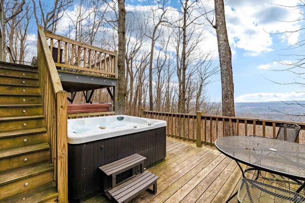 Un jacuzzi en una terraza con una mesa. en Scenic Getaway - Hot Tub & Mountain Views, en Mentone