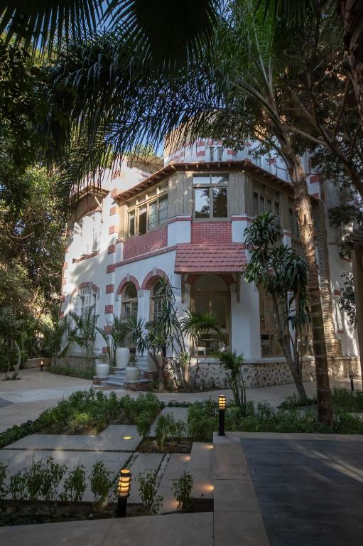 a building with palm trees in front of it at Numero CINQ Fragrance Boutique Hotel in Cairo