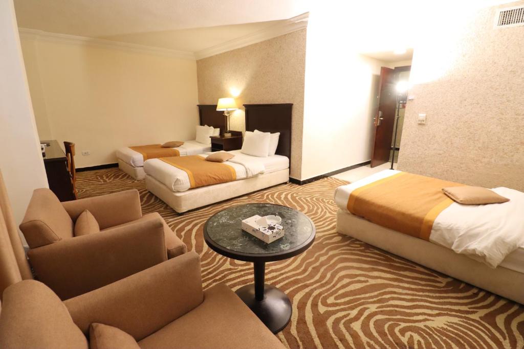 ein Hotelzimmer mit zwei Betten und einer Couch in der Unterkunft Space Hotel By Trend in Amman