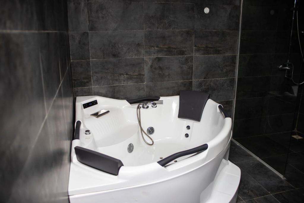 a white bath tub in a bathroom with black tiles at Noah's Ark Hotel & Suites in Maroko