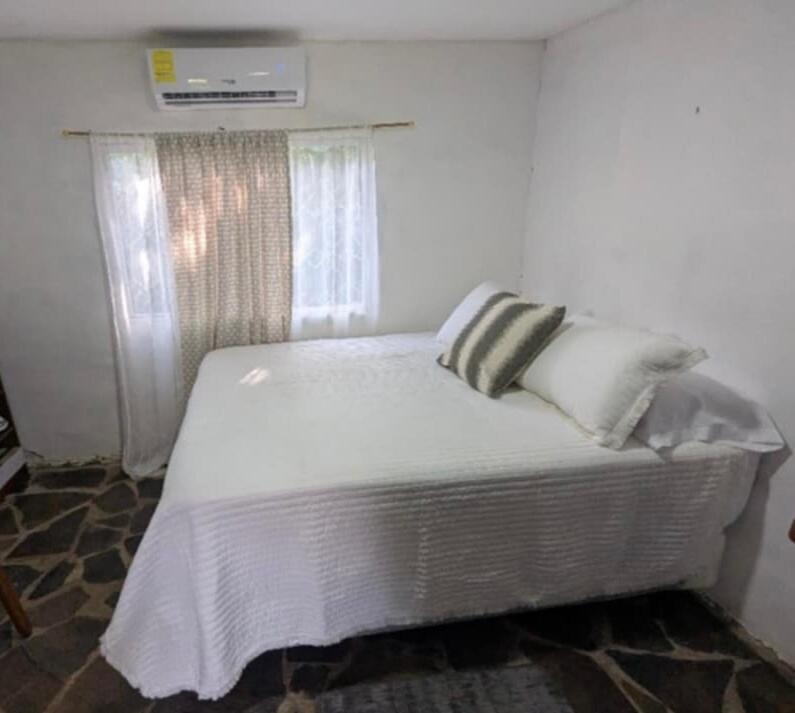 Una cama con sábanas blancas y almohadas en un dormitorio. en La Escondida, 