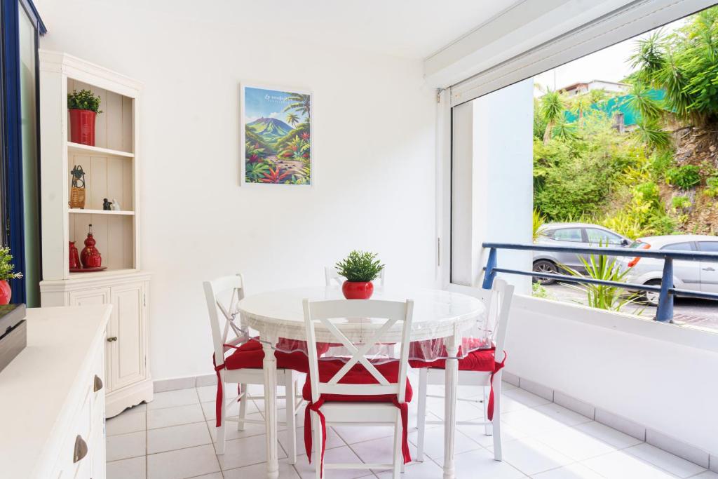 a dining room with a table and chairs and a window at Bel appartement au calme et cosy à deux pas de la plage in Le Gosier