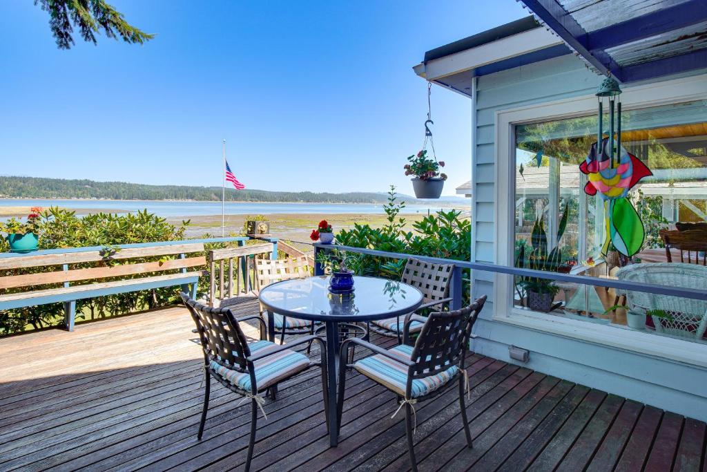a table and chairs on a deck with a view of the water at Across Water From Belfair SP Hood Canal Cottage! in Belfair