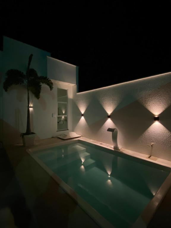 a swimming pool lit up at night with lights at casa blanca in Beberibe