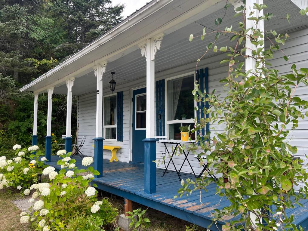 ein Haus mit einer blauen Veranda mit einem Tisch darauf in der Unterkunft La maison des Coteaux in LʼAnse-Saint-Jean