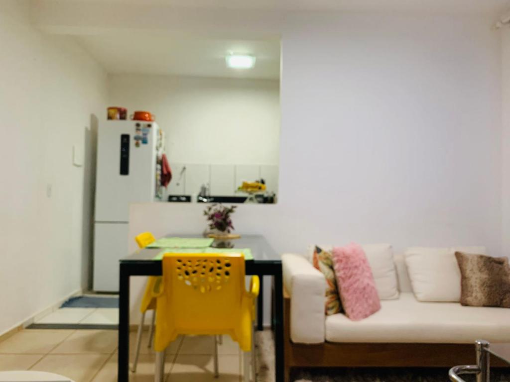 a kitchen with a couch and a table and a yellow chair at Calmo e aconchegante apartamento térreo com quintal in Valparaíso de Goiás