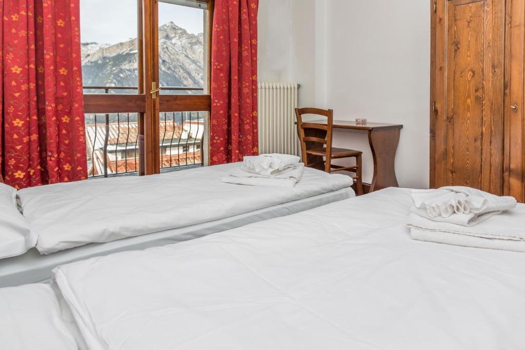 サウゼ・ドゥルクスにあるHotel La Terrazzaのベッド2台、テーブル、窓が備わる客室です。