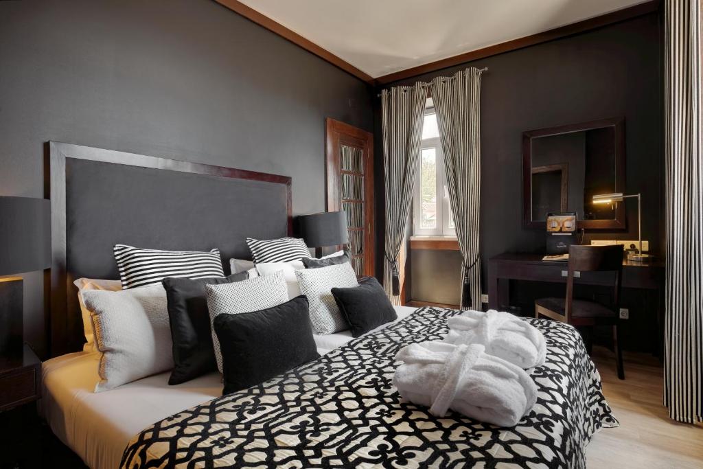 a bedroom with a large bed with black and white pillows at Hotel Inglaterra - Charme & Boutique in Estoril