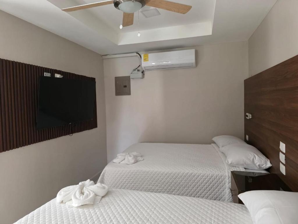 Un dormitorio con dos camas y un televisor de pantalla plana. en Hostal Boutique Isabel, en Managua