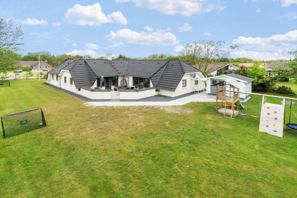 a house with a black roof on a yard at BV185-Blavand-Degnevangen-5 in Blåvand