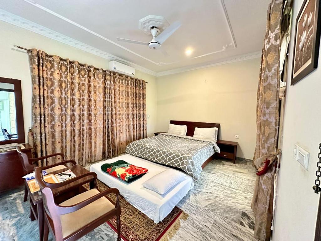 a bedroom with a bed and a table and a chair at Ziel Hotels & Guest House Islamabad Near US Embassy & VFS Global in Mohra Nūr
