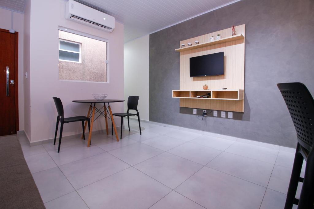 a room with a table and chairs and a tv at LOFT PAJUMAR 1 ANDAR 300mt PRAIA PAJUCARA in Maceió