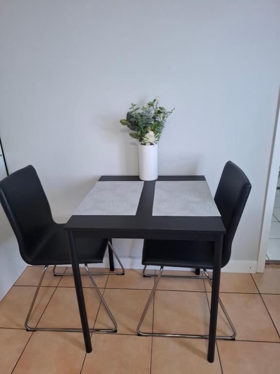 a black table with two chairs and a potted plant at Top of the Mark in Gold Coast