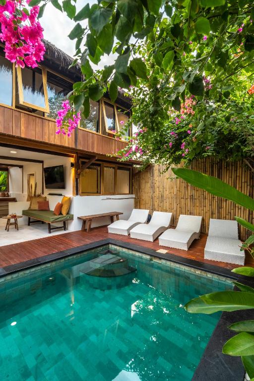 a pool with chairs and a house with flowers at Villa Tiga - Spacious 3BR villa in central Gili Air perfect for families & groups in Gili Islands
