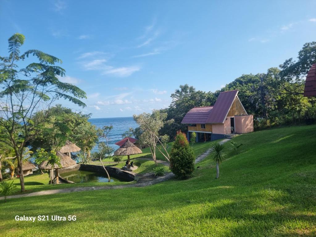a house on a hill next to the ocean at Puri Ma'u Beach & Bungalows in Boba