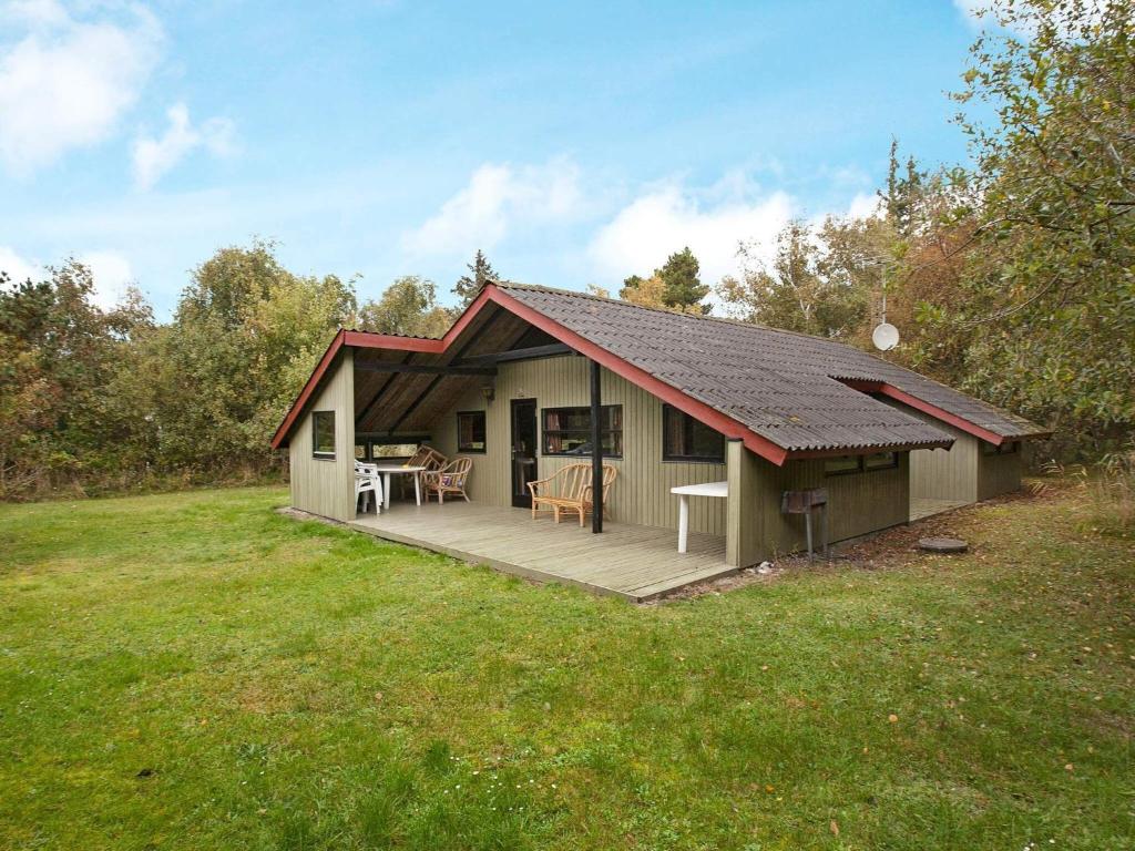 a small house with a deck in a field at Holiday Home Escape in Scenic Rodby in Rødby