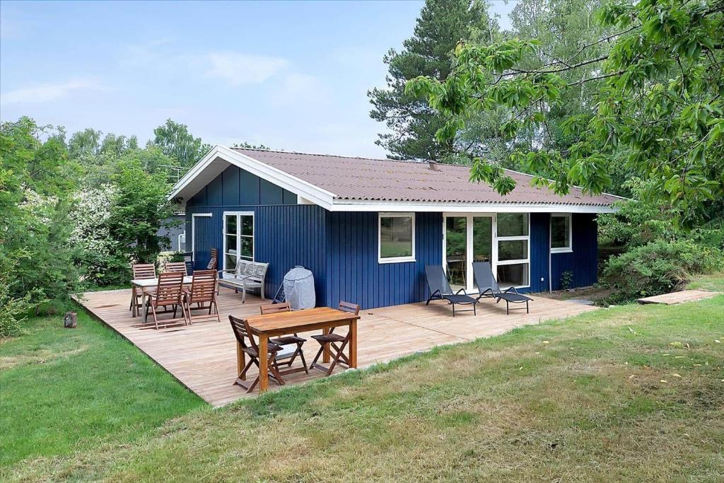 a blue house with a table and chairs on a deck at 13365-Asnaes-Radyrvej-63 in Asnæs