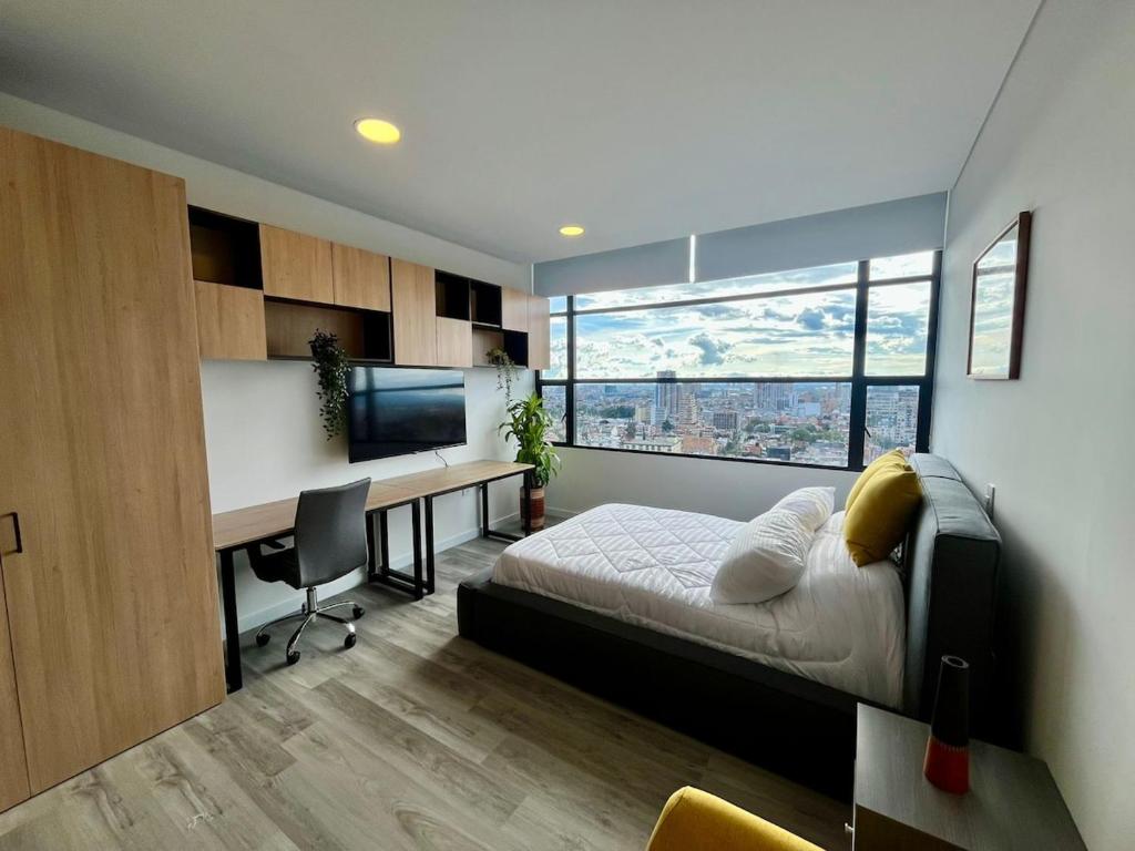 a bedroom with a bed and a desk with a computer at Tu espacio acogedor en el Centro Internacional in Bogotá
