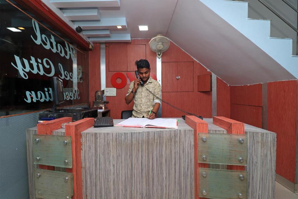 a man talking on a cell phone at a desk at Hotel O Steel City in Jāmul