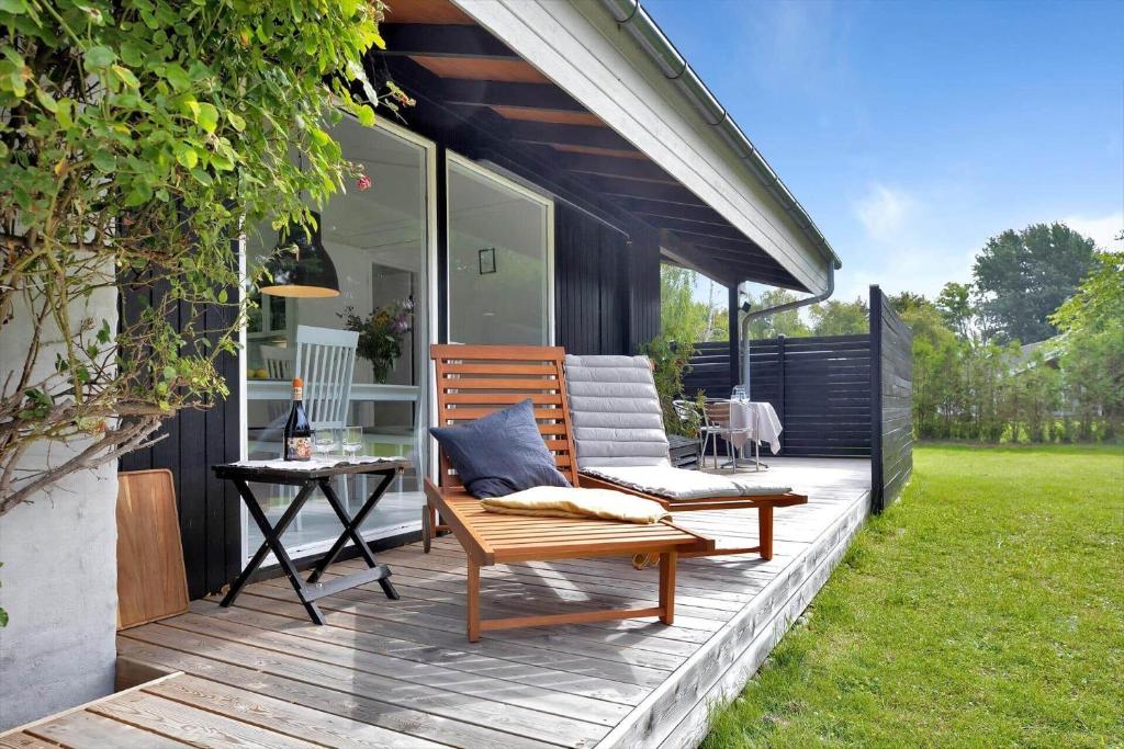 a wooden chair sitting on a deck with a table at 12280-Sjaellands-Odde-Pumavej-8 in Tjørneholm