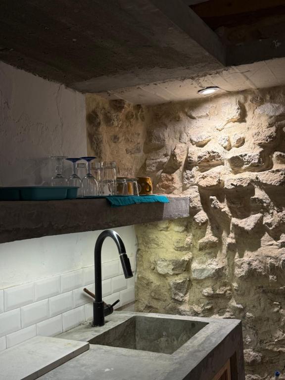 Una cocina con fregadero y una pared de piedra. en Casa Dea - bungalow Mykonos, en Hammamet Sud