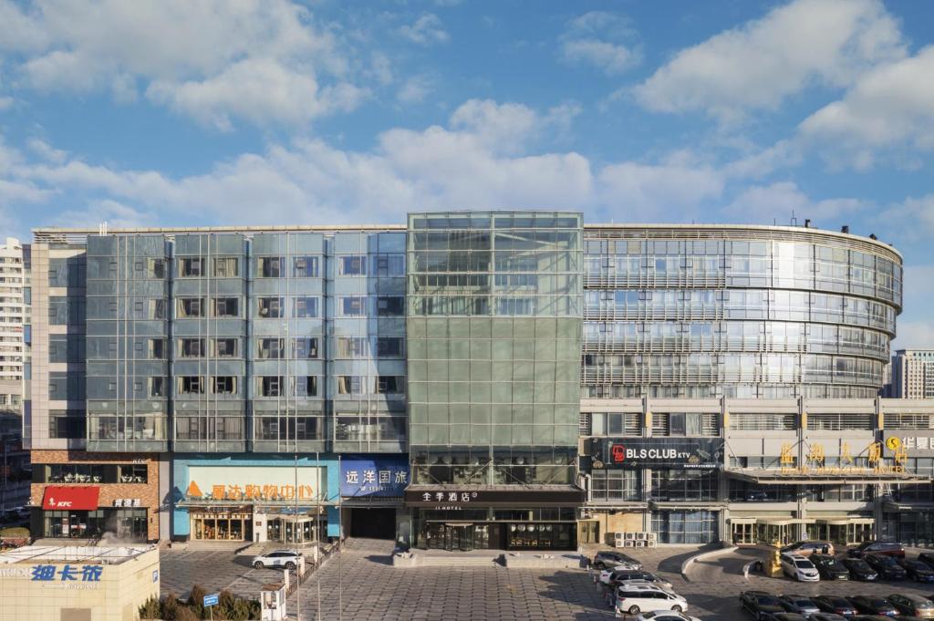 a large glass building with a parking lot in front of it at JI Hotel Qingdao Laoshan Stone Man Bathing Beach in Qingdao