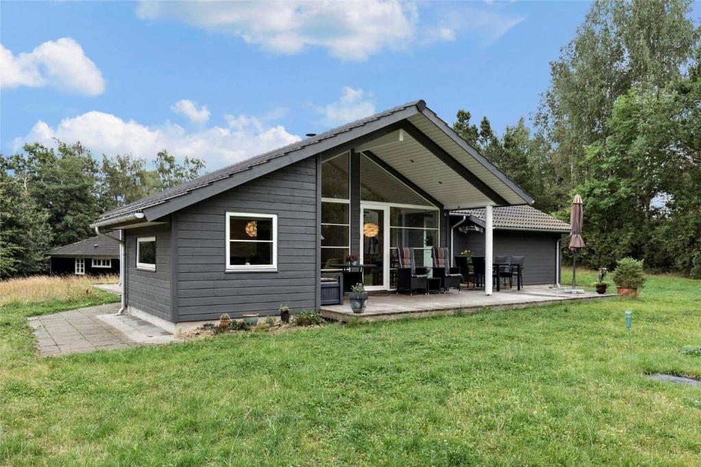 a small black house with a porch and a yard at 11802-Nykobing-Sj-Gogetoften-10 in Nyrup