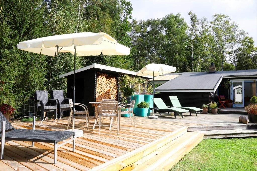 10013-1-Nykobing-Sj-Chr-Petersensvej-35 في Rørvig: سطح خشبي مع كراسي ومظلة