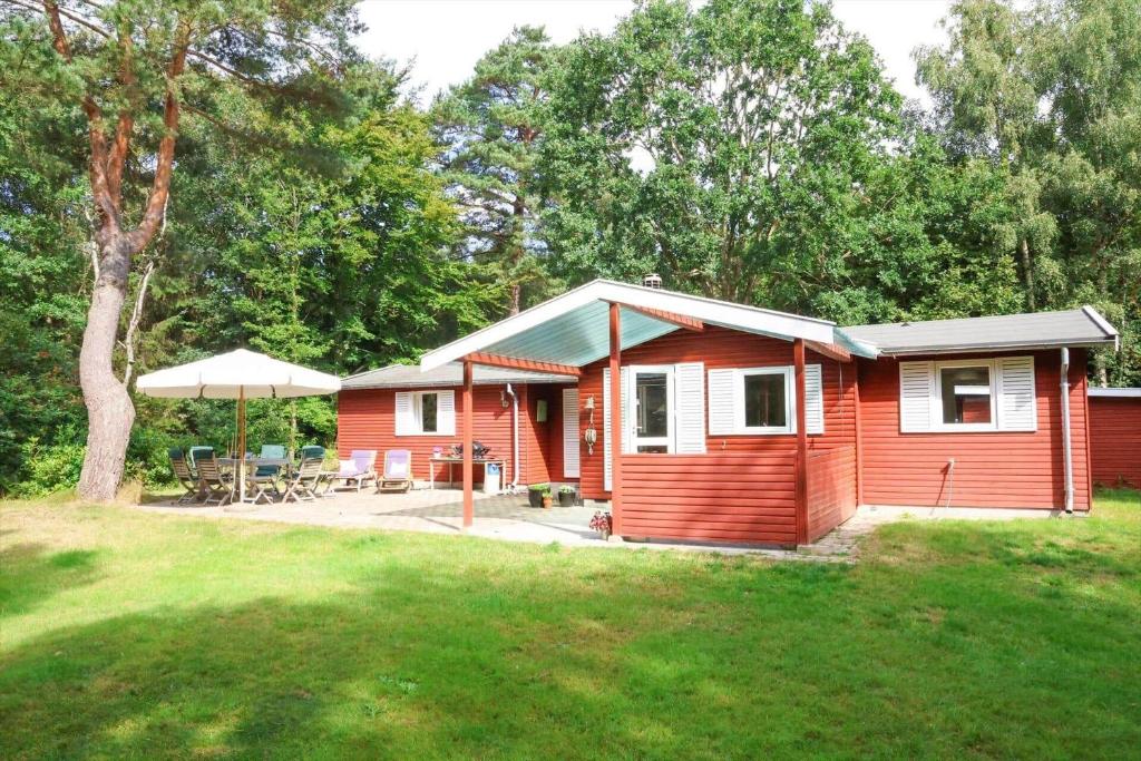 a small red cabin with a patio and umbrella at 10033-1-Rorvig-Hjortevej-17 in Rørvig