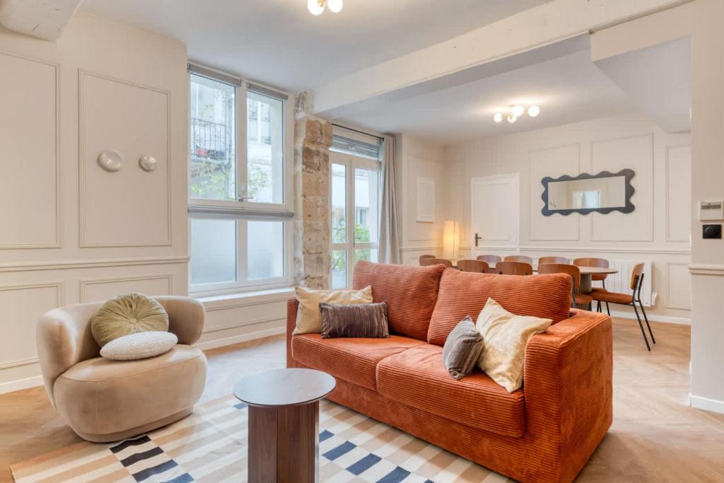 Splendid 10PAX apartment in the center of Paris في باريس: غرفة معيشة مع أريكة برتقالية وكرسي