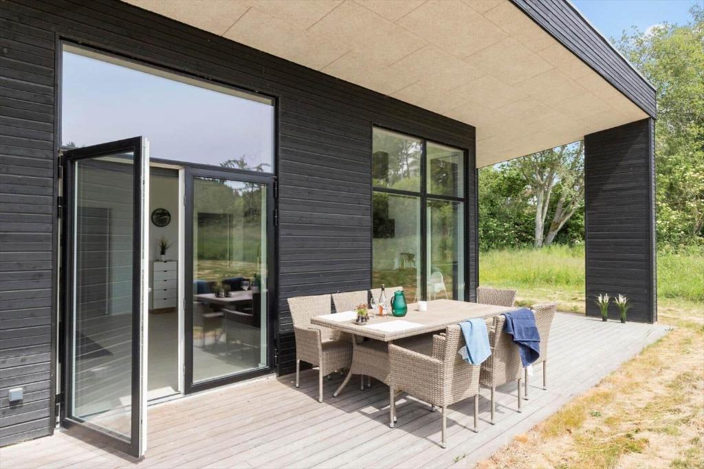 a house with a table and chairs on a deck at 84160-Ebeltoft-Baekholmen-5-A in Ebeltoft