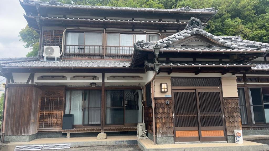an asian house with an asian roof at みなと館 華 in Sukumo