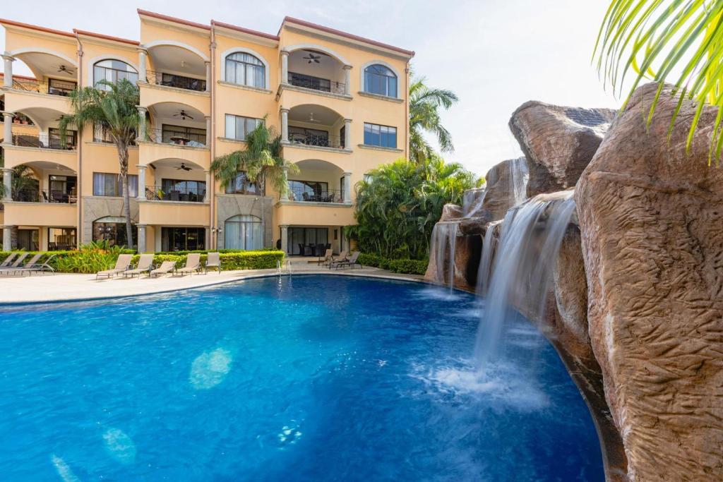 a pool with a waterfall in front of a hotel at Sunrise 7 - 2 Bedroom, Ocean View Condo in Tamarindo