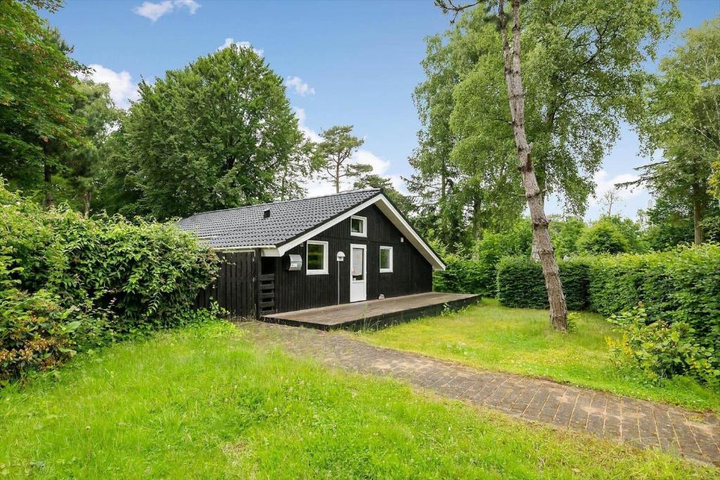 a small black cabin in the middle of a yard at 8116-Ega-Under-Ronnene-37 in Egå