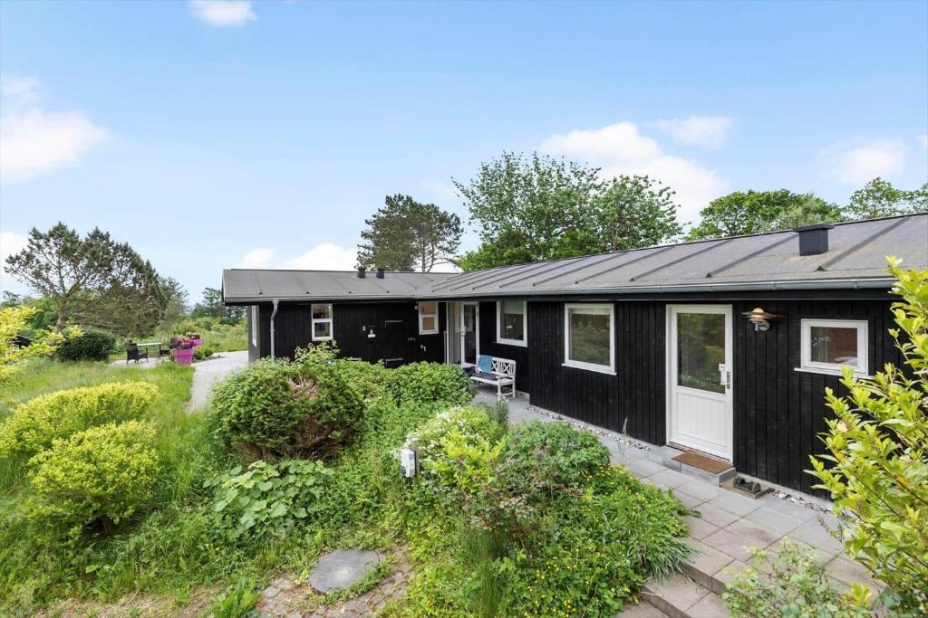 a black house with a garden in front of it at 84159-Ebeltoft-Koravej-5 in Ebeltoft