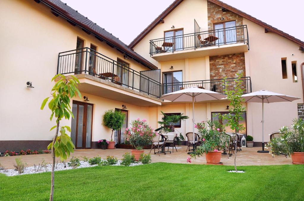 une maison dotée d'une terrasse avec des tables et des parasols dans l'établissement Barackvirág Apartmanház, à Tihany