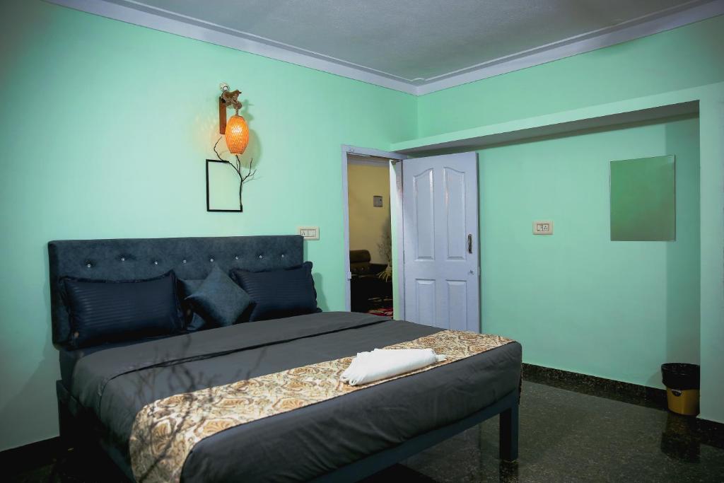 a bedroom with a bed with a blue wall at Wild Wood Stays in Madikeri