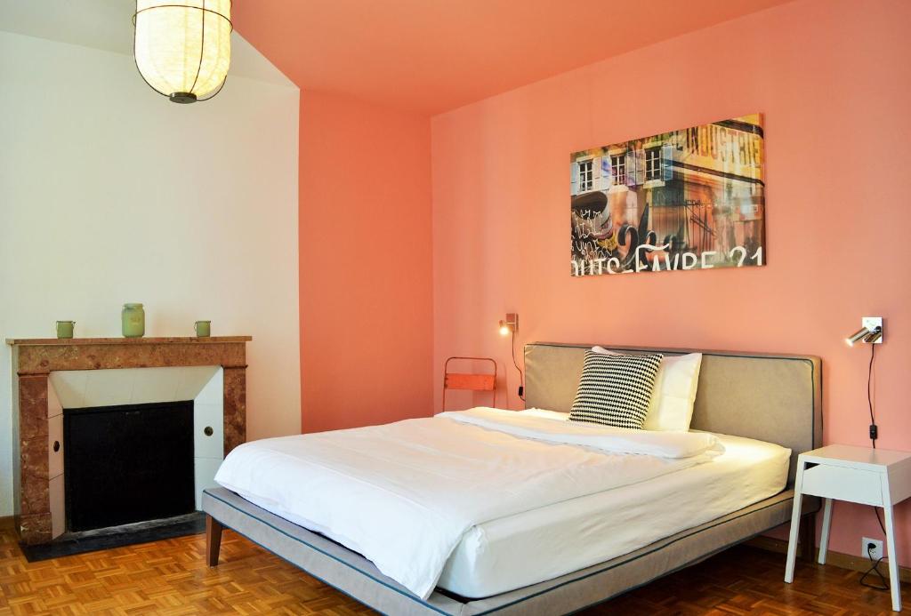 1 dormitorio con pared de color naranja, cama y chimenea en B&B Louis-Favre 21, en Neuchâtel