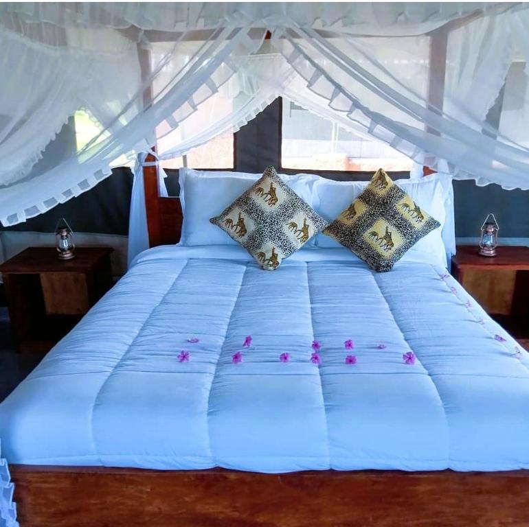 a bed with white sheets and pillows in a room at Endeem mara resort in Ololaimutiek