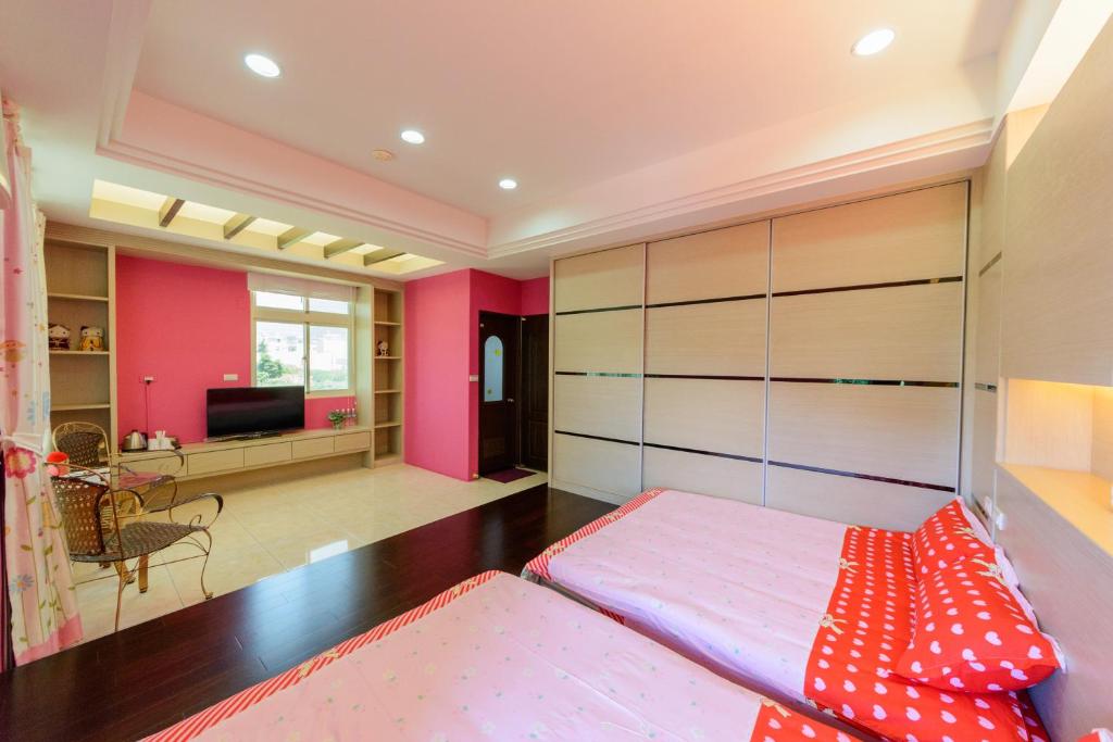 a bedroom with pink walls and a bed with red pillows at Hualien Macaron B&amp;B in Ji&#39;an