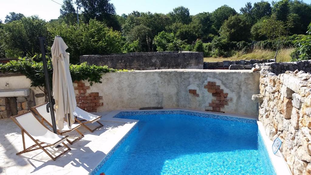 a swimming pool with two chairs and an umbrella at Holiday home Olea in Malinska