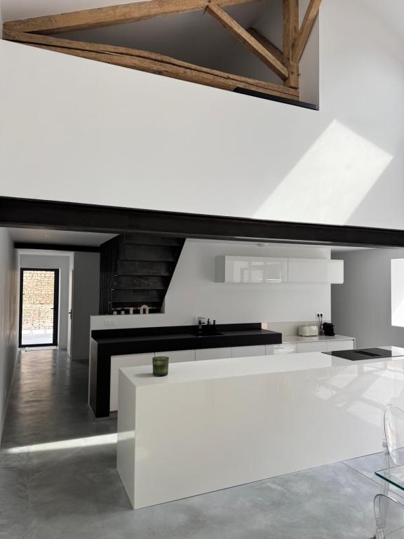 a white kitchen with a white table in a room at Il Clovio - Discreet luxury, close to Futuroscope in Jaunay-Marigny