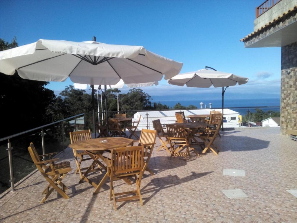 a patio with tables and chairs and umbrellas at Marficas Hostel in Urzelina