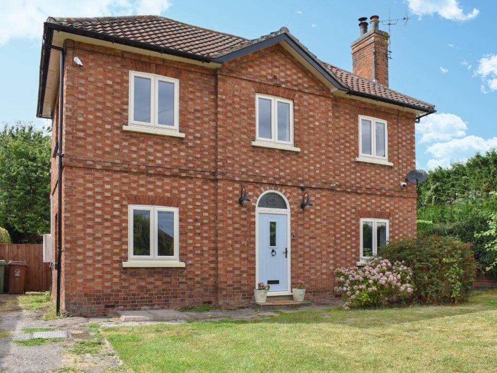 a red brick house with a white door at Lanes Farm in Eakring