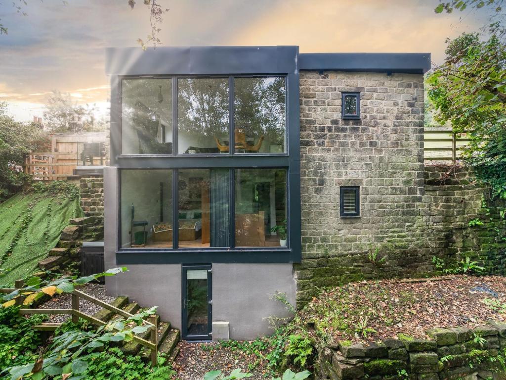 a brick house with large glass windows at The Keep in Hebden Bridge
