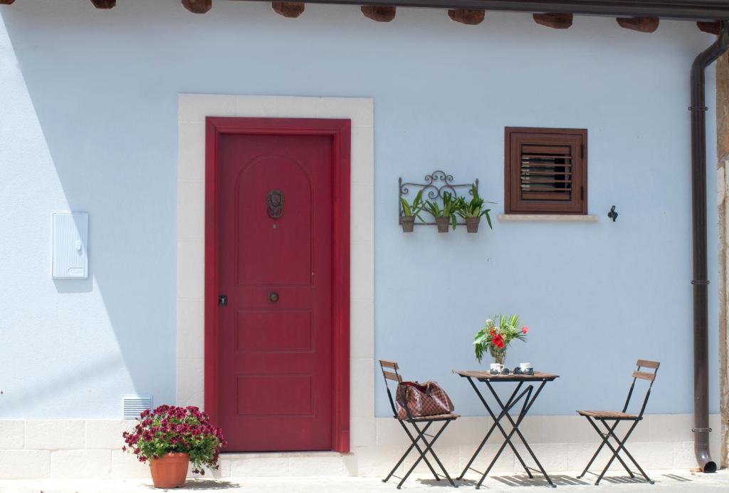 een rode deur op een witte muur met een tafel bij Le case del Duca in Ioppolo Giancaxio